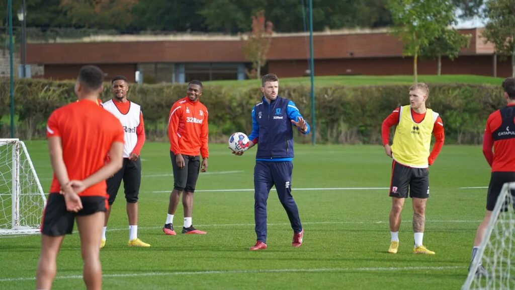 Michael Carrick discussing strategies with assistant coaches during a training session.