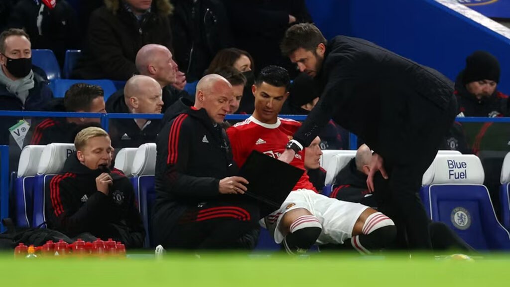 Michael Carrick giving instructions to Cristiano Ronaldo with assistant coaches from Manchester United on the bench.