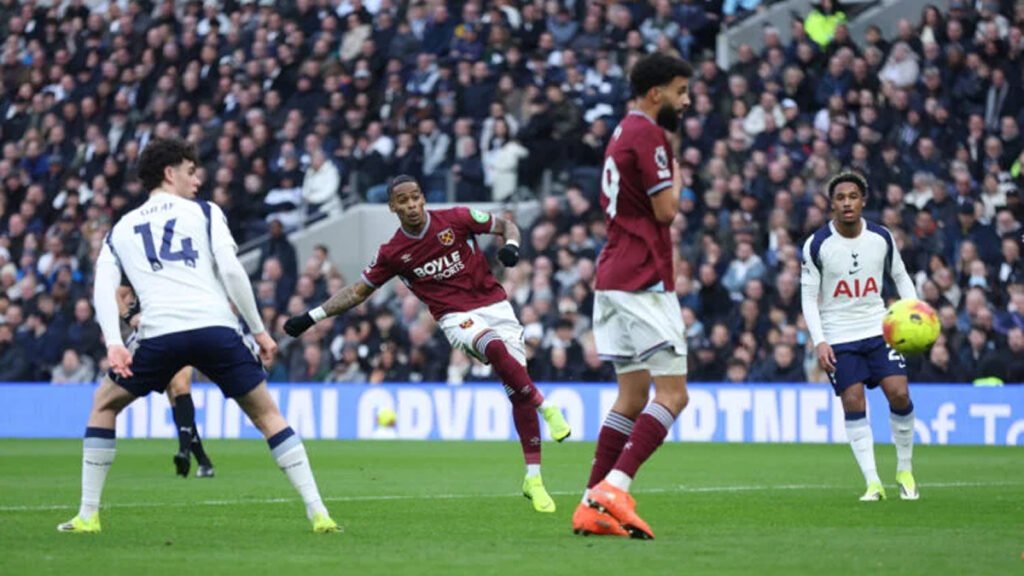 West Ham player strikes the ball as Tottenham defenders watch
