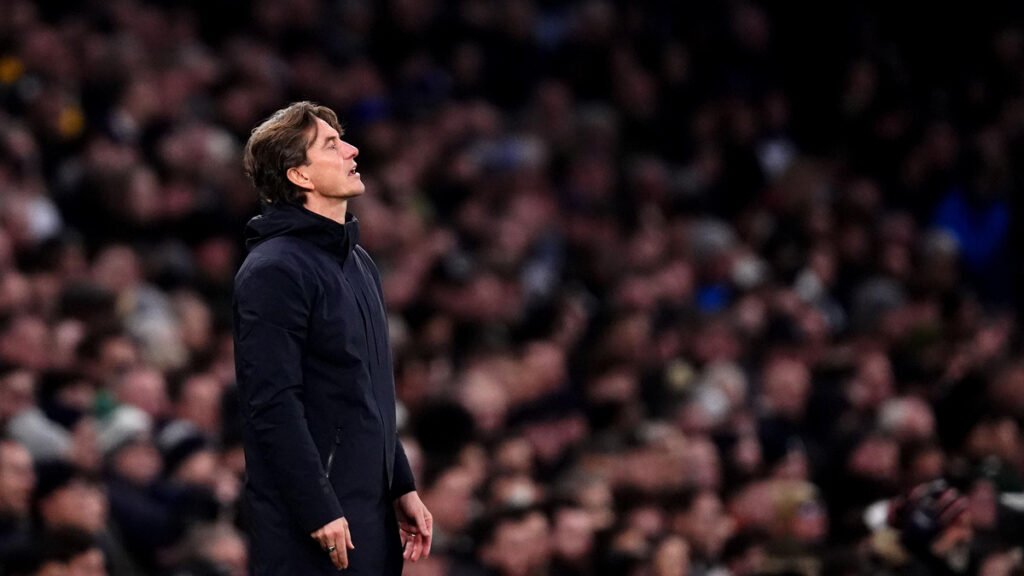 Tottenham coach watches from the touchline with blurred crowd behind