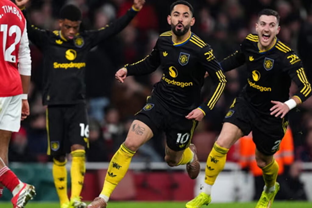 Manchester United players celebrate a goal as away fans react