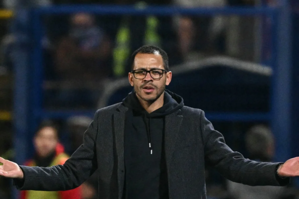 Liam Rosenior seated on Strasbourg’s bench during a Ligue 1 match, observing the game with focus.