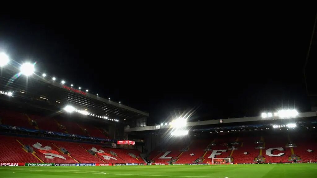 Anfield stadium exterior shows Liverpool crest under floodlights
