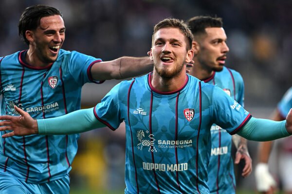 Semih Kılıçsoy celebrates a goal in Cagliari colours with the crowd blurred behind him