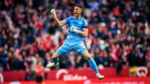 Sevilla keeper saves a penalty, diving left as the ball is pushed away