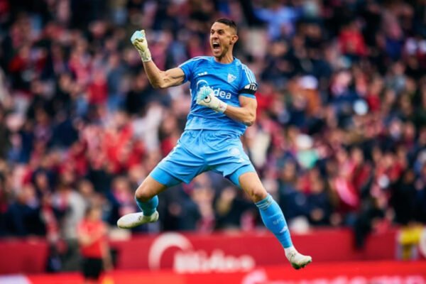 Sevilla keeper saves a penalty, diving left as the ball is pushed away