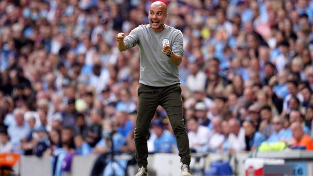 Pep Guardiola gestures instructions from the touchline during a Manchester City match.