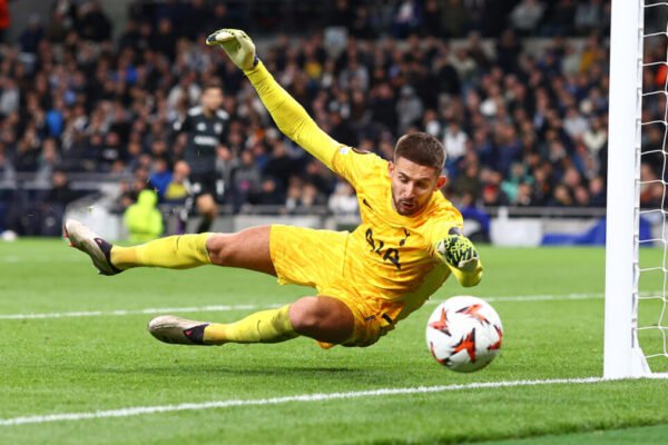 Guglielmo Vicario dives to save in a Tottenham match, gloves outstretched.