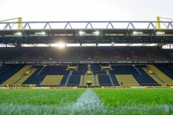 Packed stadium under floodlights with a wall of yellow-and-black supporters.
